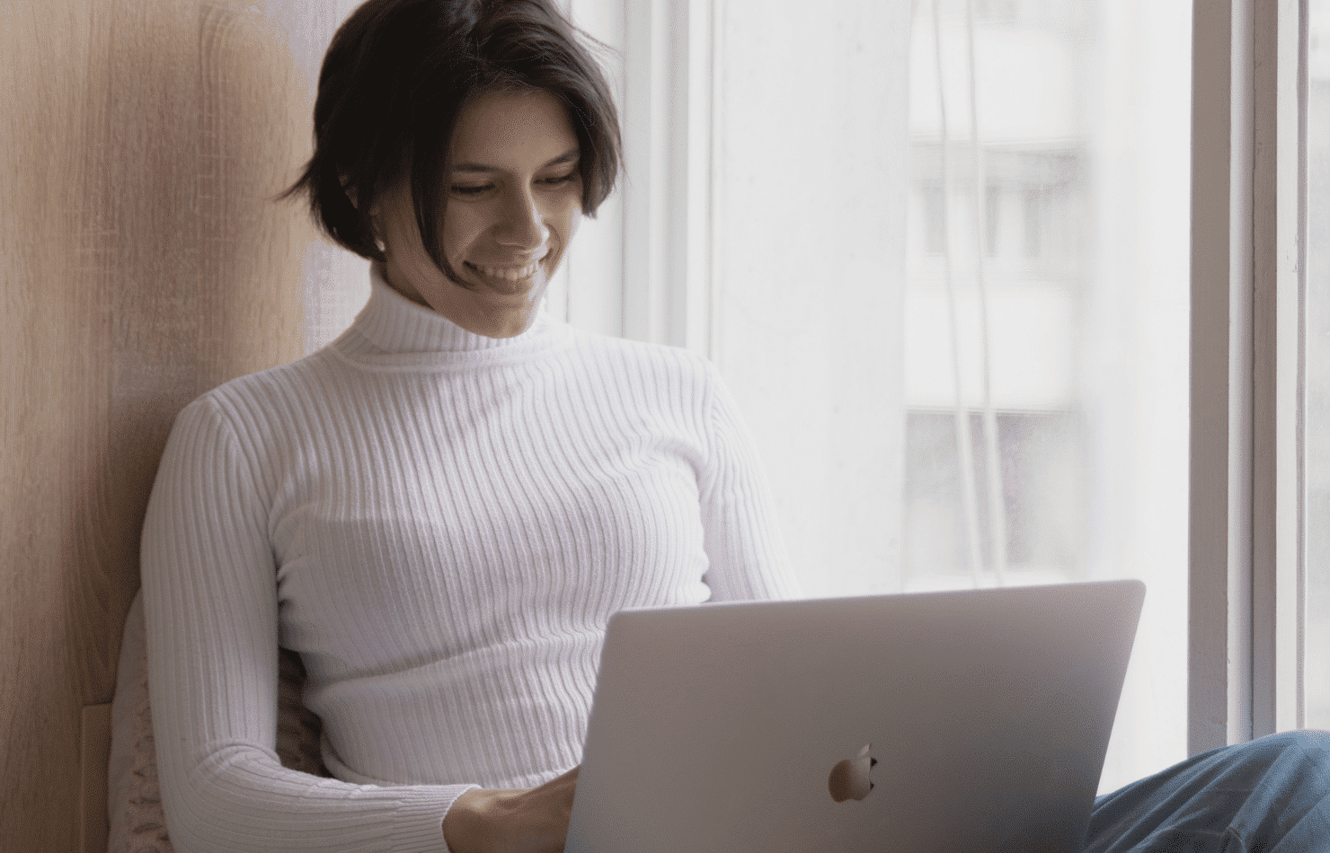 Woman near window using a Mac