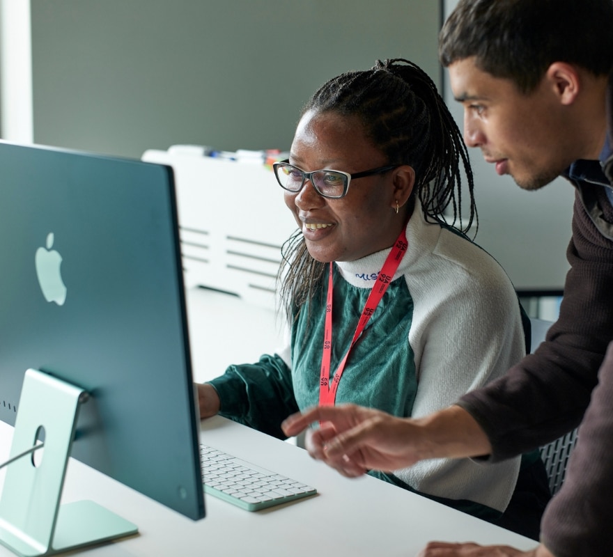 A man and a woman working on an iMac together