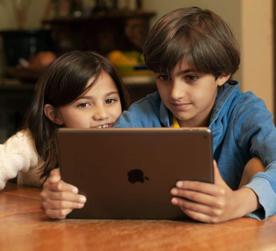 Two children using their iPad at home.
