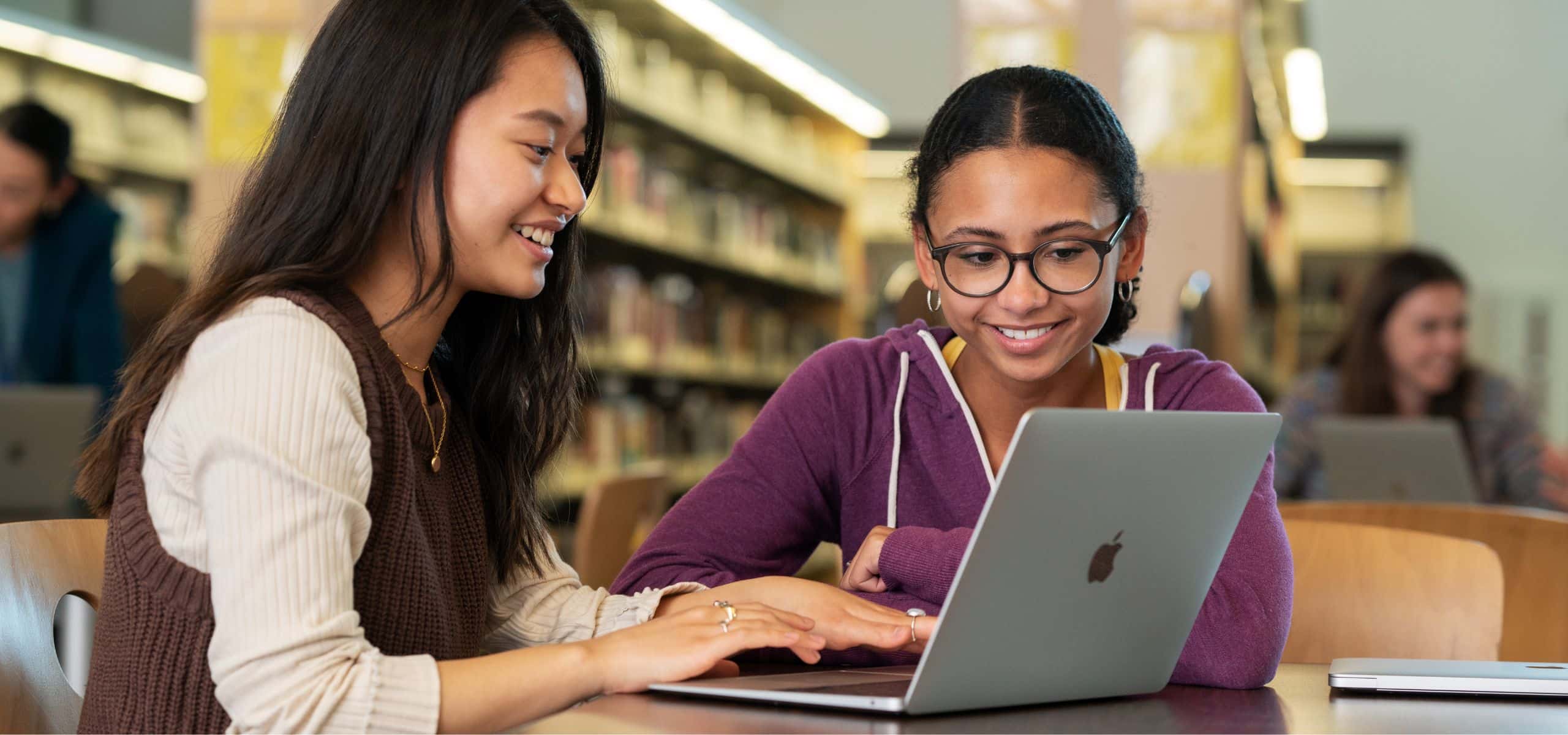 A parent helping their child with thir homework on a Mac.