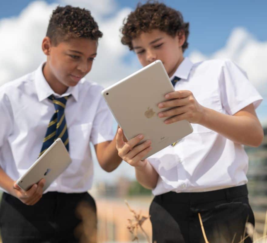 Two students using their iPad devices outside of the classroom, to take part in practical learning beyond the classroom.