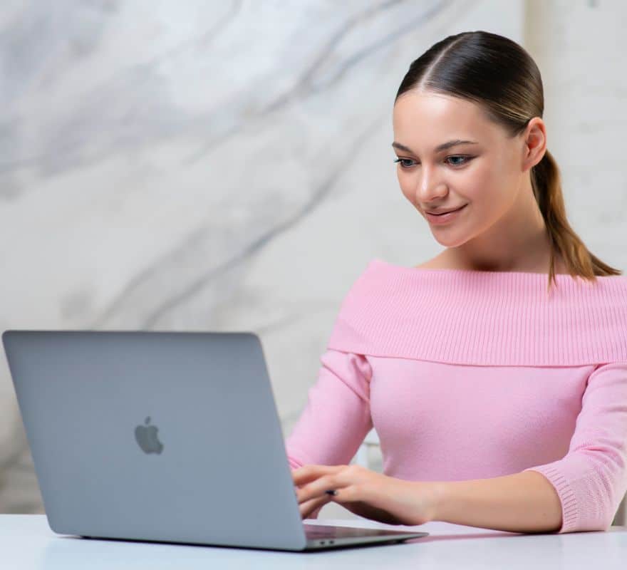 Happy lady using a Mac to enhance productivity within her Government role.