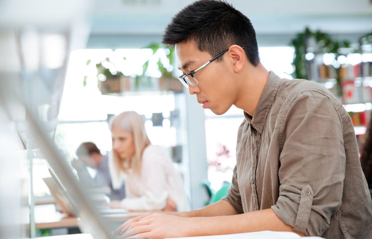 A student with glasses working on a Mac during their science lesson.