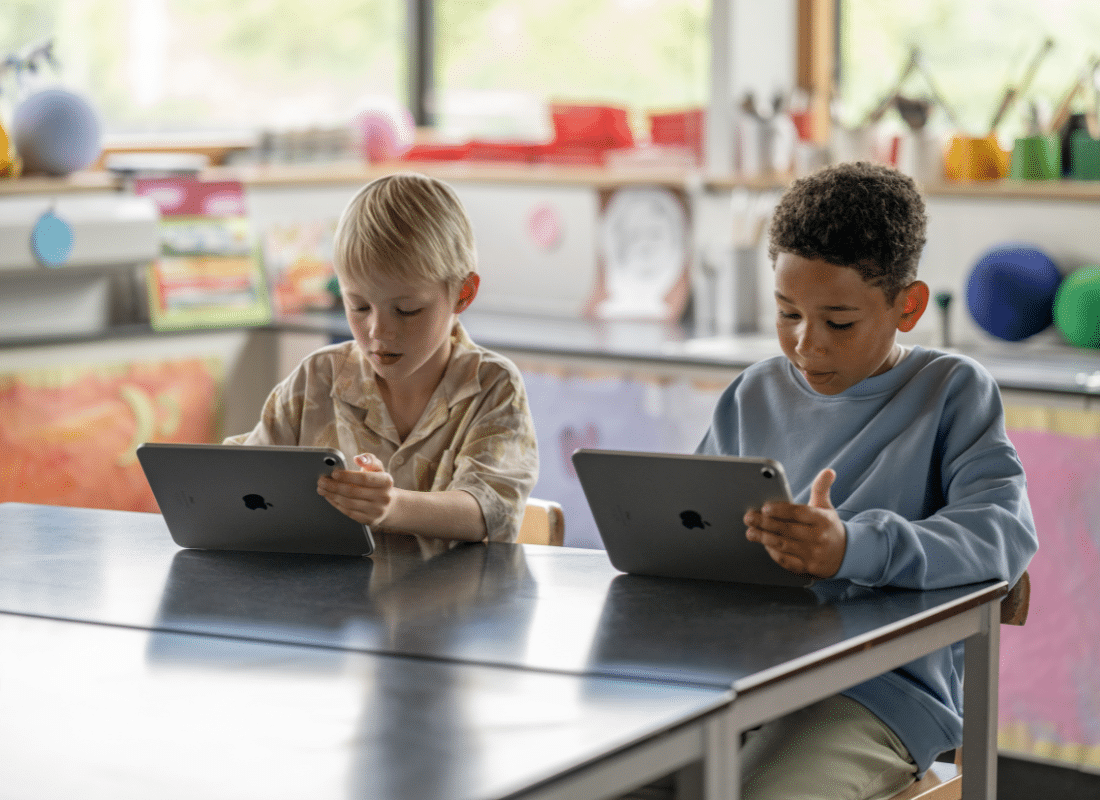 Two male students work side by side on their iPad devices