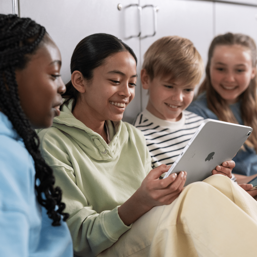Four students gather around an iPad in the classroom