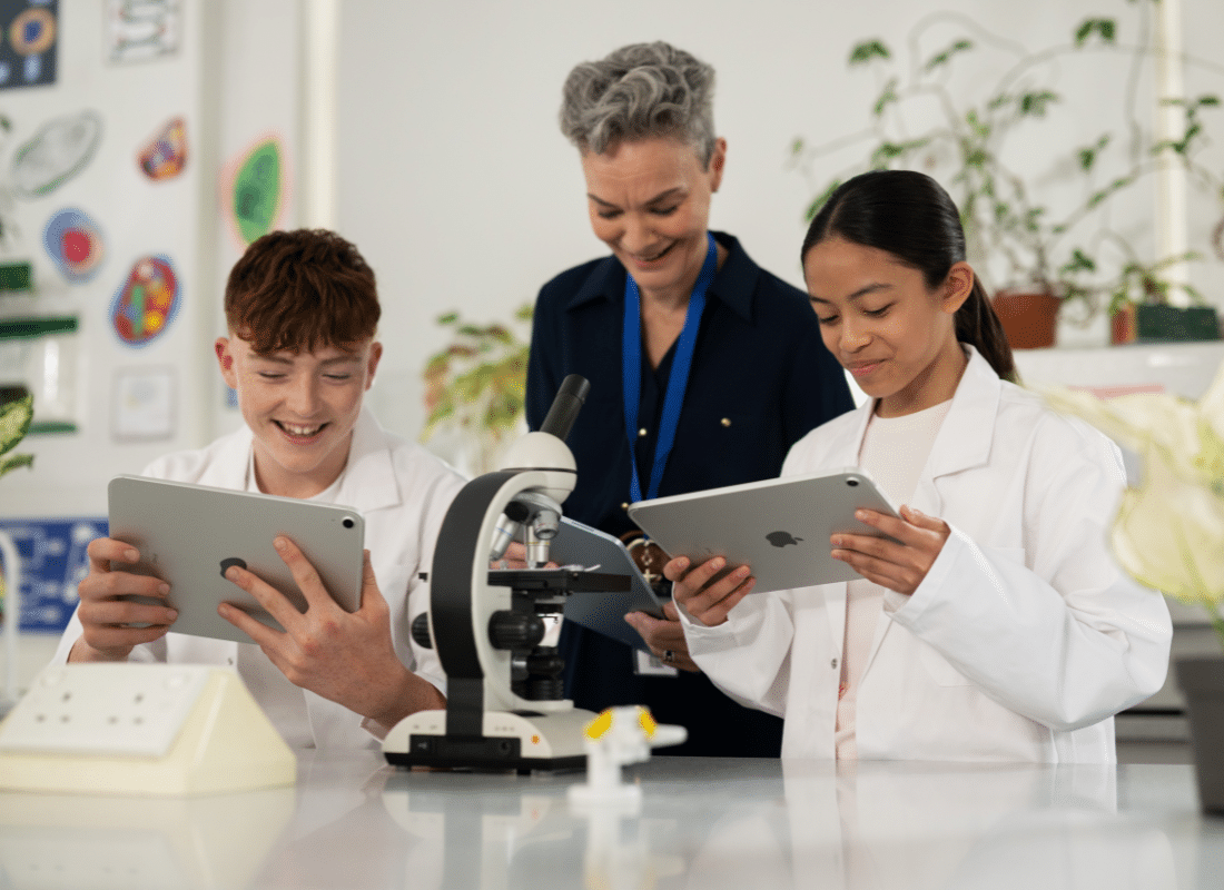 Teacher and two students collectively using iPad devices together in Science class