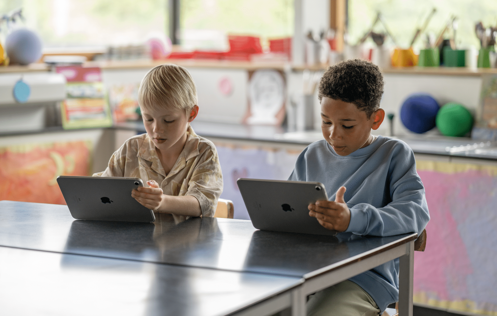 Two pupils working at a table on their iPad devices