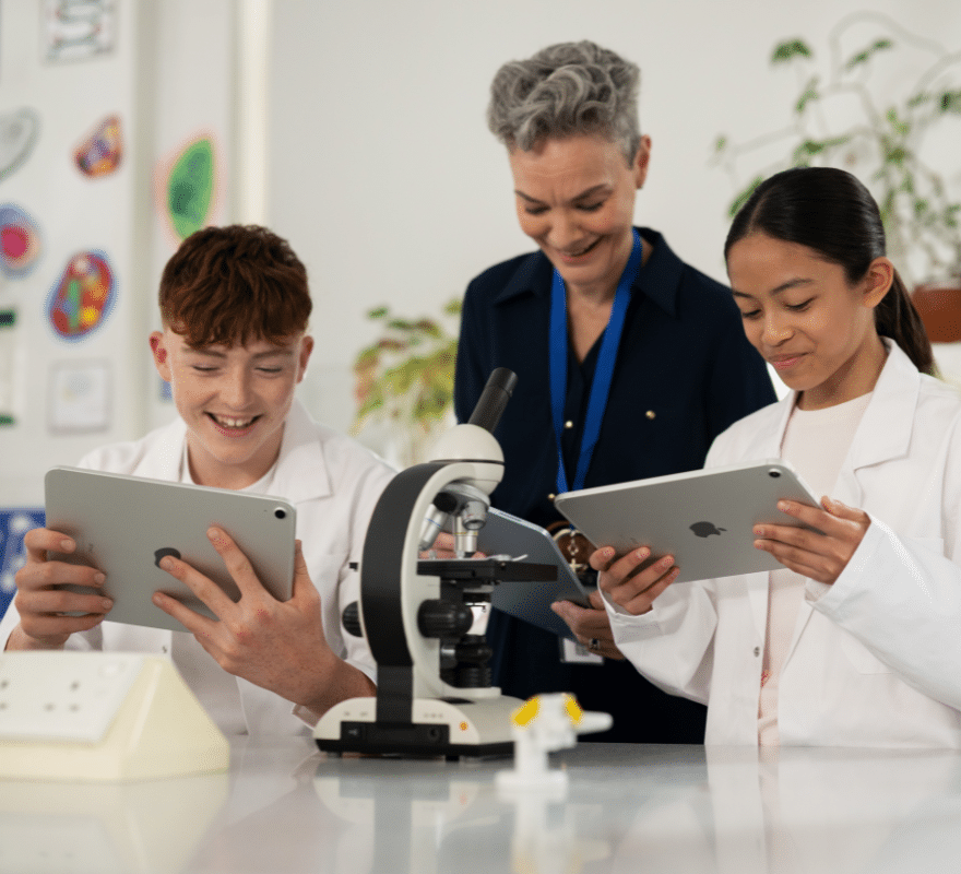Teacher and two students collectively using iPad devices together in Science class