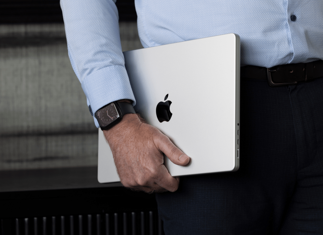 Employee holding a Mac device under his arm while showing off his Apple Watch