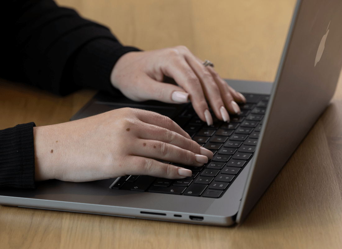 Close up of female employee typing on the keyboard of her Mac device