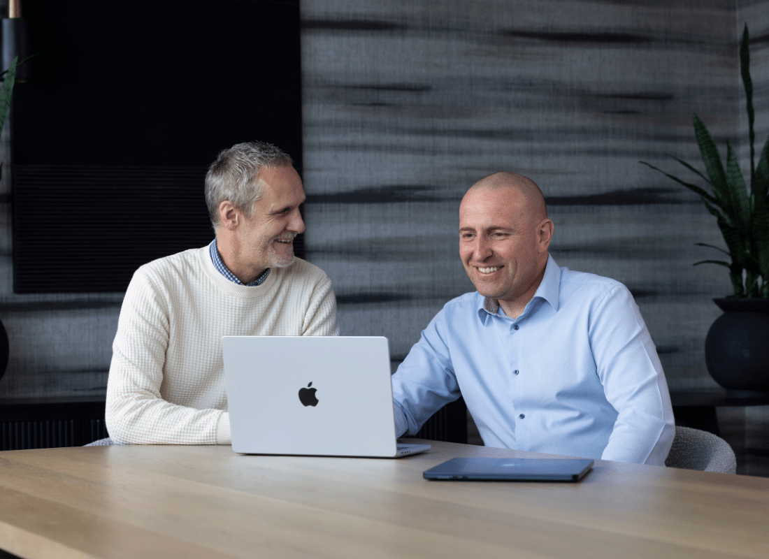 Two employees working on a Mac device together